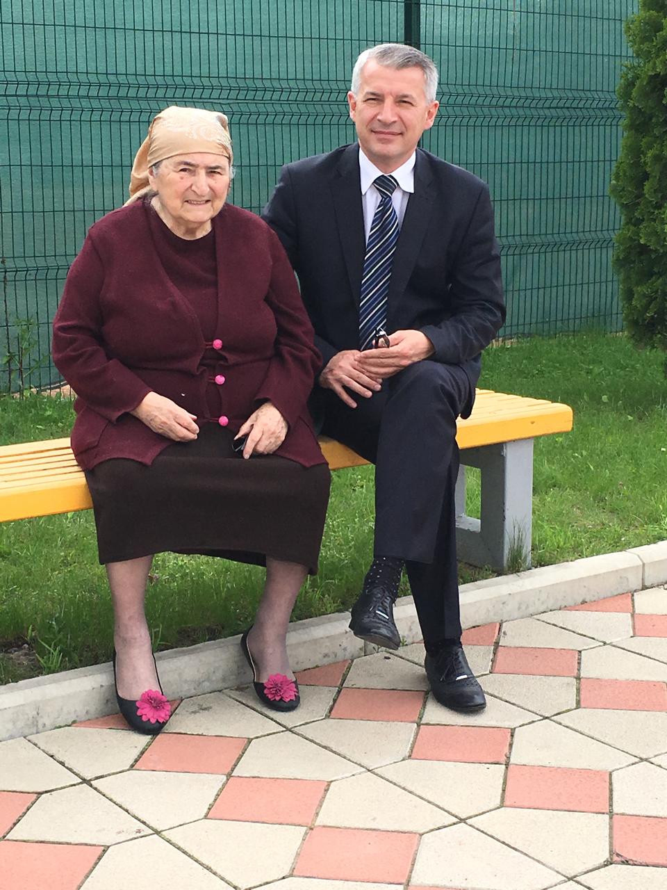Два человека сидят на скамейке на открытом воздухе